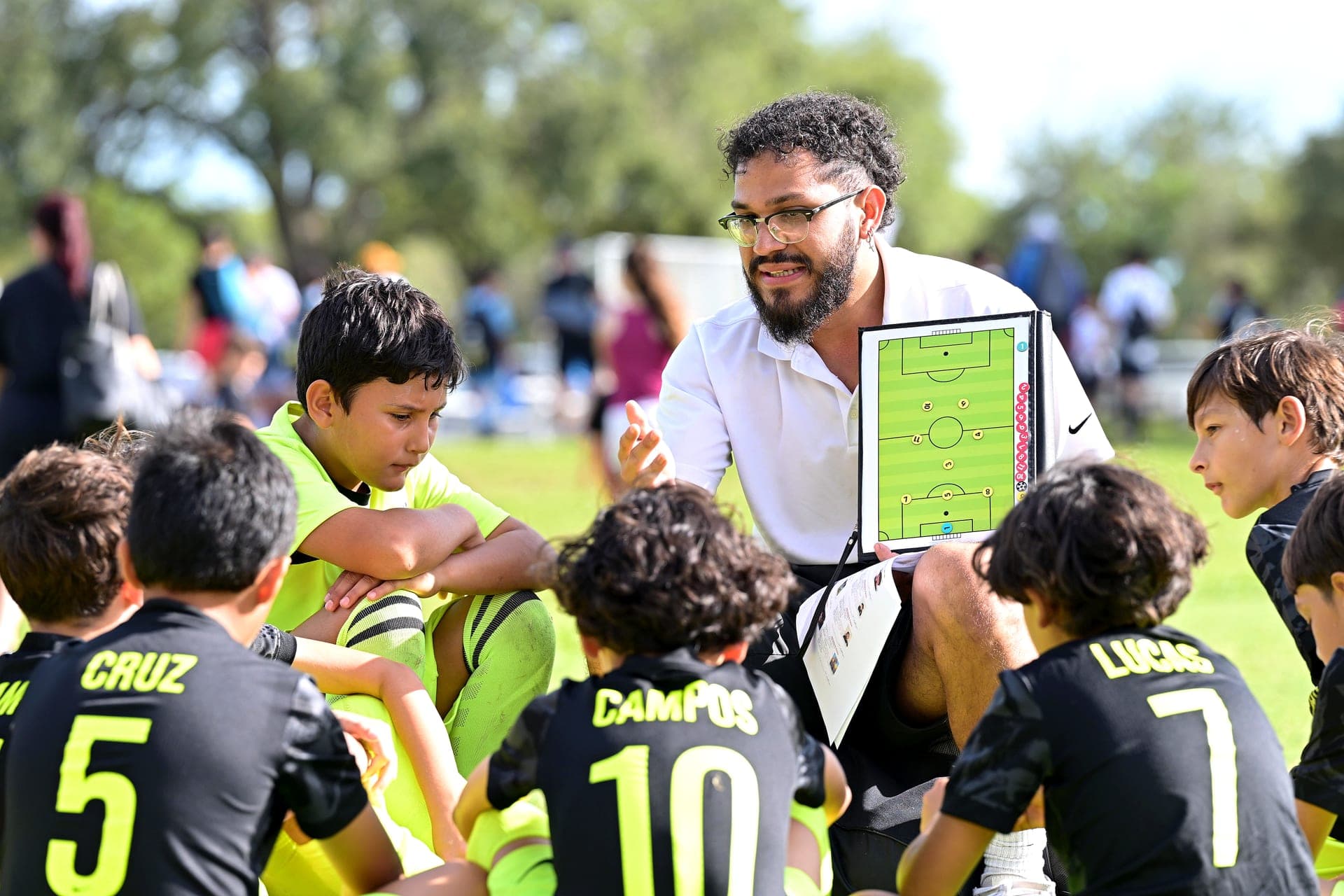 Arena Strikers coach going over tactics on a board with his players sitting around him on match day