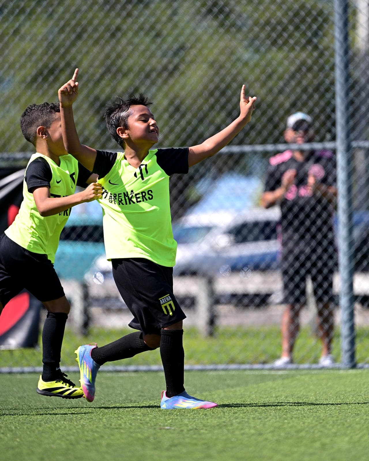 Arena Strikers player celebrating a goal with both fingers pointing up as a teammate runs to join him