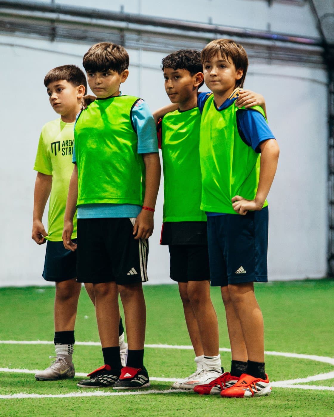 Four campers in bibs standing arm in arm on the indoor field