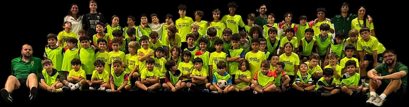 Arena Strikers Summer Camp 2026: campers in lime camp shirts and bibs sitting and standing in rows with their coaches