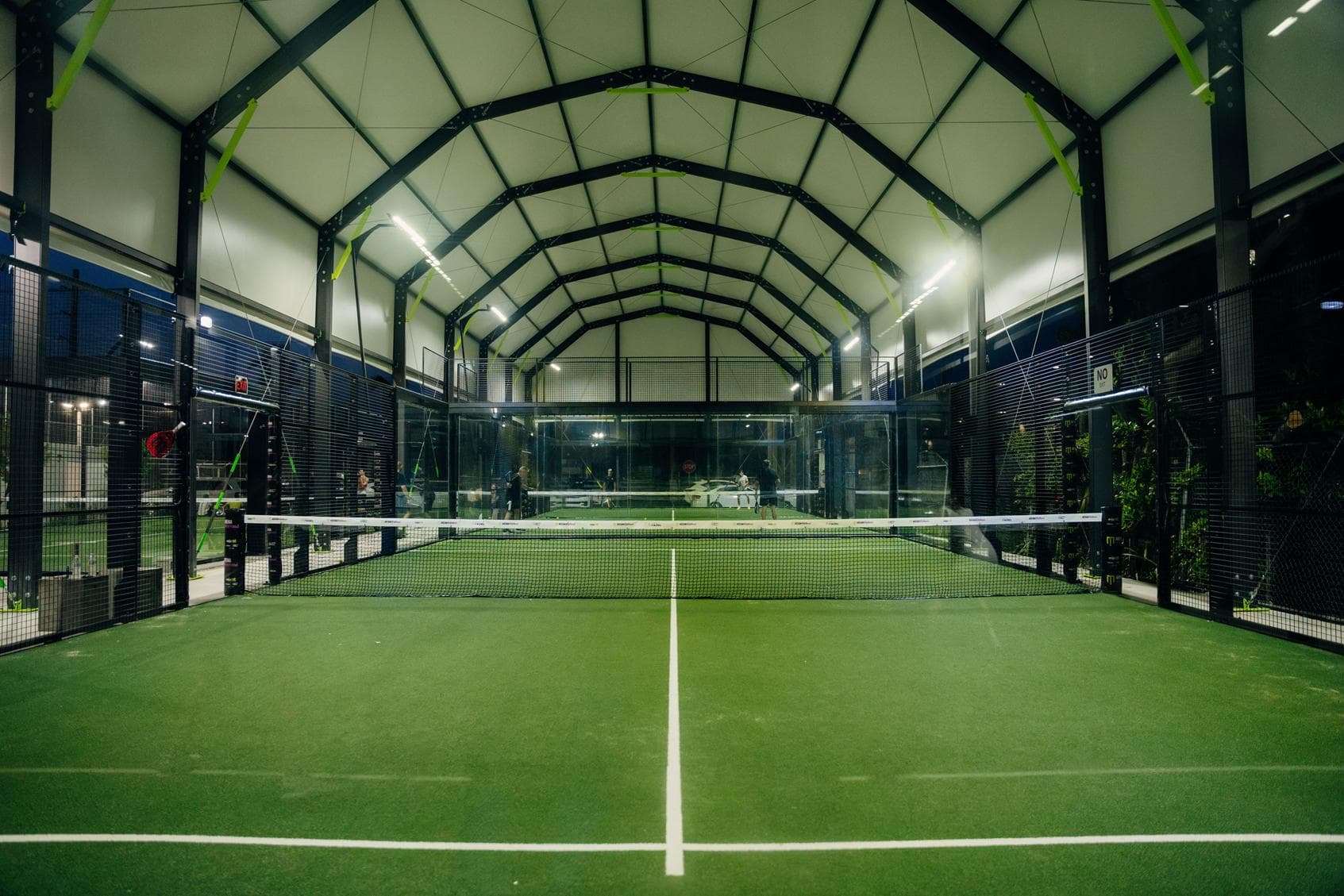 Covered padel courts in a row under one long roof at night at Arena SSC Wynwood, Miami