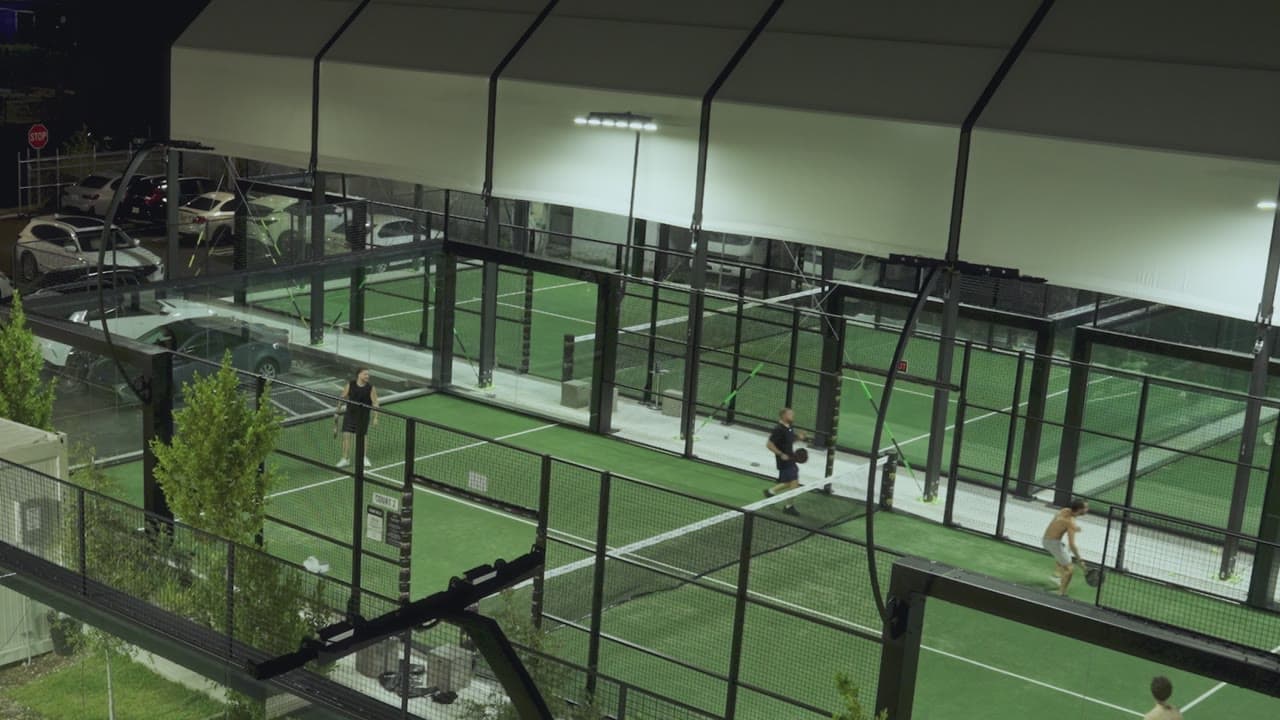 The covered padel courts at Arena SSC Wynwood from above at night, with players on court