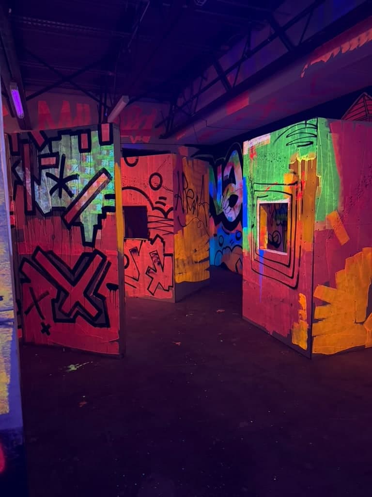 The laser tag arena at Arena SSC Wynwood: fluorescent graffiti walls and barriers under blacklight (6 of 9)