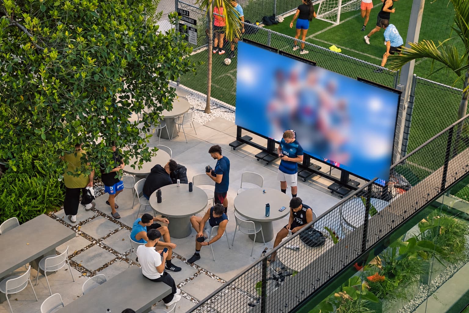 The outdoor LED screen at Arena SSC Wynwood over the patio tables, with players sitting around after a game