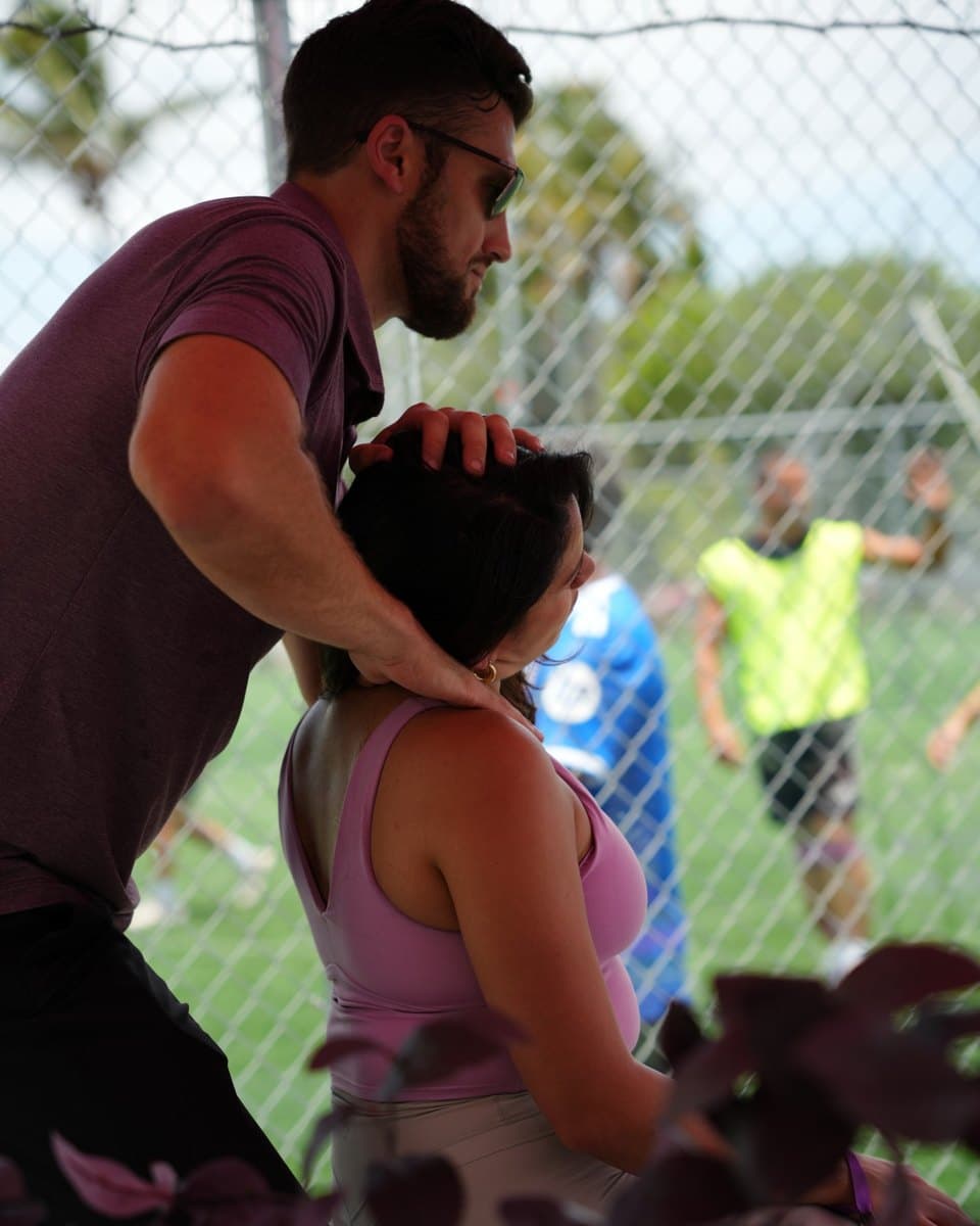 A recovery massage at a wellness morning at Arena SSC Wynwood, with a soccer game behind the fence